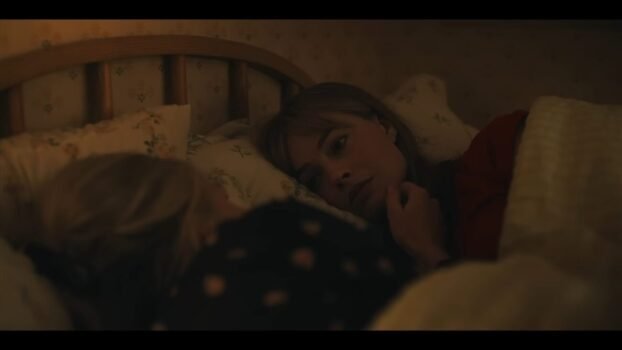 Sarah (Margot Robbie) is in bed with her mother in front of her comforting her