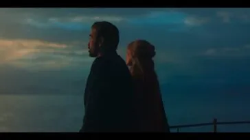 David (Colin Farrell) and Sarah (Margot Robbie) standing next to each other looking at the blue horizon.