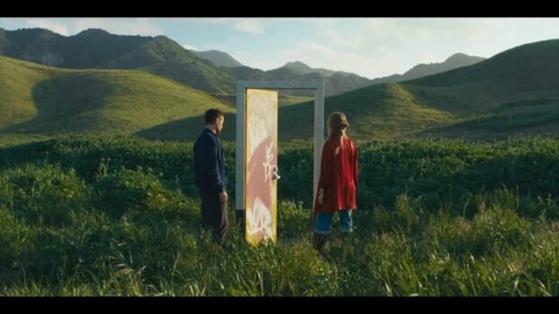 David (Colin Farrell) and Sarah (Margot Robbie) stand next to a door in a field with grass.