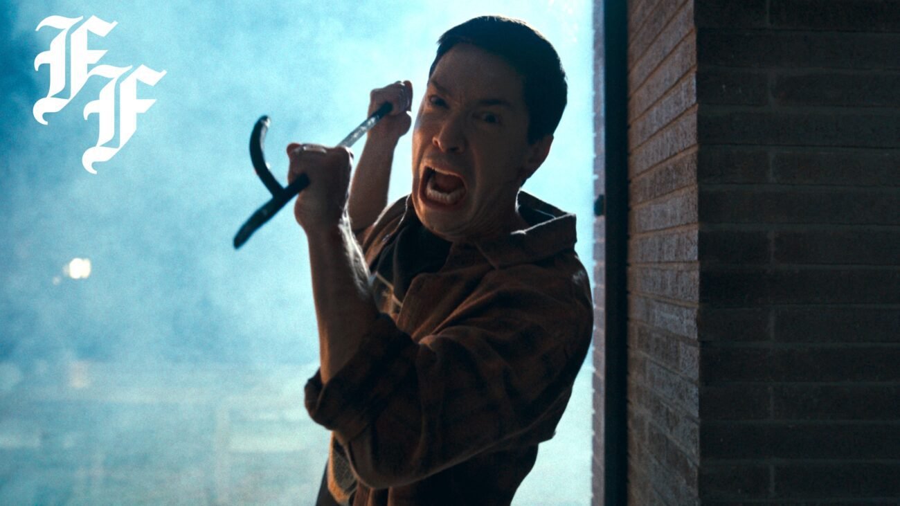 A man with an intense face, screams as he approaches the camera with a firepoker.