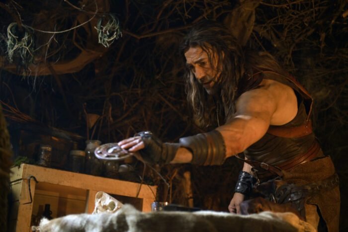 a man holds an amulet in a cave.