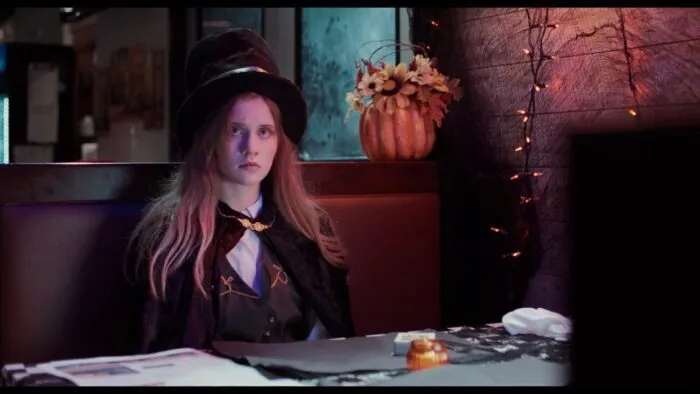 Max, dressed as a magician, sits in a restaurant booth.