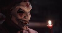 The jester's mask is lit by a candle.
