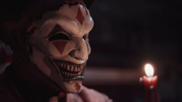 The jester's mask is lit by a candle.