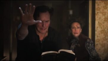 a man with his hand extended reading from a book and a scared and worried woman over his shoulder.