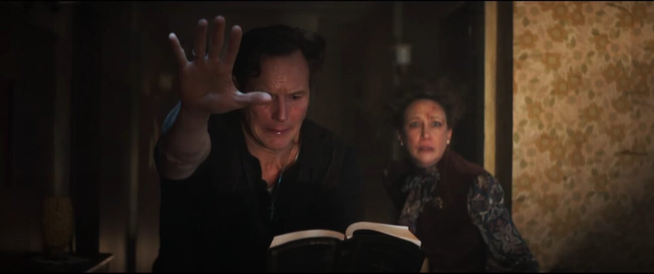 a man with his hand extended reading from a book and a scared and worried woman over his shoulder.