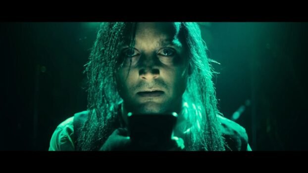Fritz (Elijah Wood) talks into a radio with greenish lighting