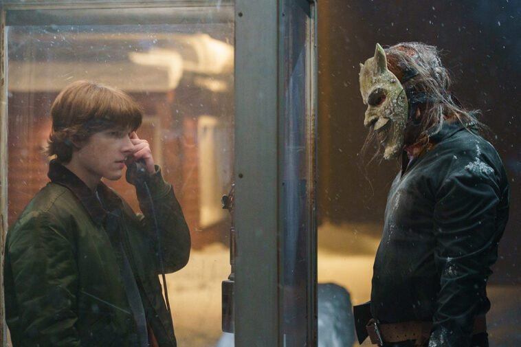 Finney (Mason Thames) stands in the Phone Booth facing The Grabber (Ethan Hawke) outside.