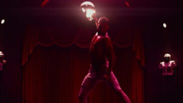 Cam (Tyriq Withers) pulls back a punch. He's in a room in all red