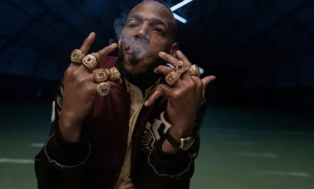 Isaiah (Marlon Wayans) shows off his rings on his fingers and smokes a cigar.