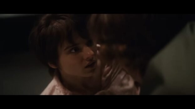 Gwen (Madeleine McGraw) is leaning back while looking at Finney (Mason Thames).