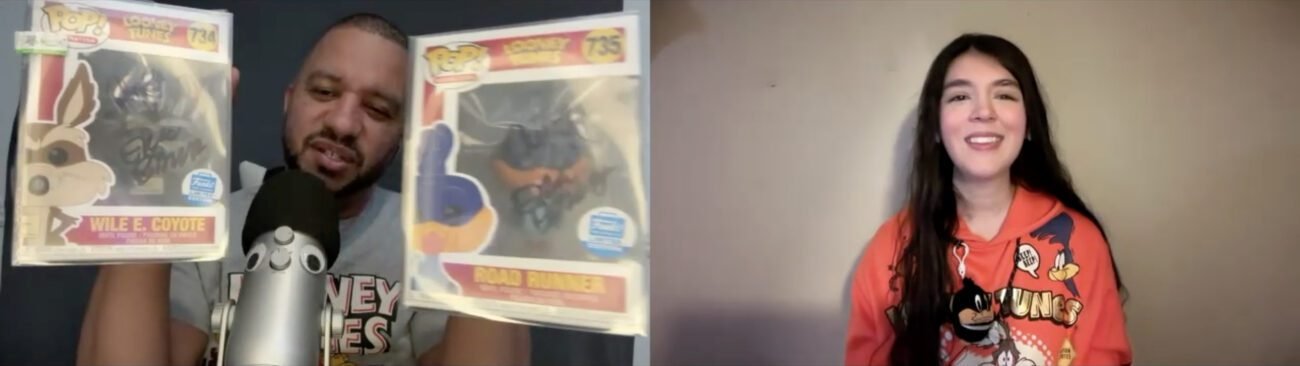 Steven Ray Byrd, wearing a Looney Tunes T-shirt, holds up Wile E. Coyote and Road Runner Funko Pops in autographed boxes while talking to Jamie Lee, wearing an orange Looney Tunes hoodie featuring Wile E. Coyote and Road Runner, a Daffy Duck key chain tied to one string on the hoodie.