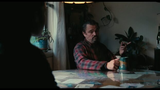 Bob (Leonardo DiCaprio) sits at a table talking to his daughter, Willa.
