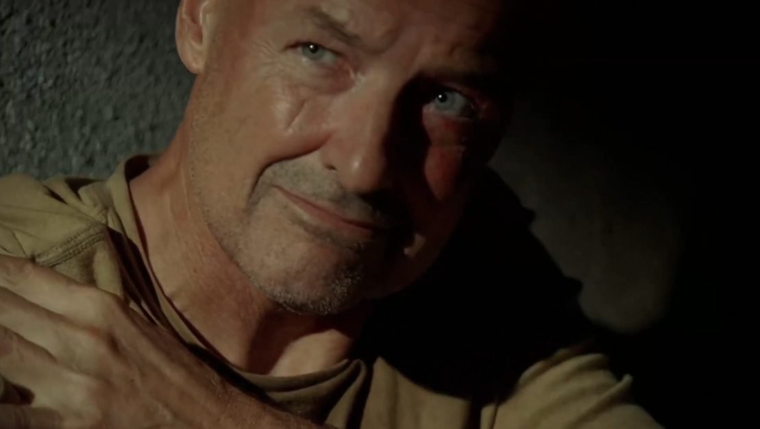 John Locke LOST A man looks past the camera, he is wearing a green shirt and has his hand over the his shoulder.