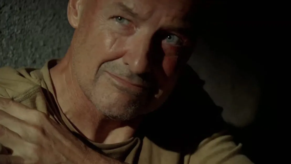 John Locke LOST A man looks past the camera, he is wearing a green shirt and has his hand over the his shoulder.