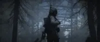 A man in a long coat and gasmask with a rifle over his shoulder walks through a dark forrest. He turns and looks at the camera