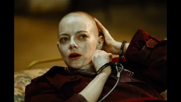 Michelle (Emma Stone) runs her hand along her head wondering where her hair is. Her face is covered in creme, and she is laying back.