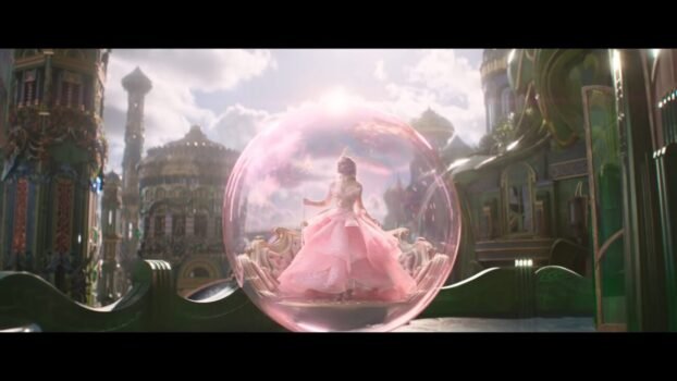 Glinda (Ariana Grande) in her pink bubble standing on a platform.