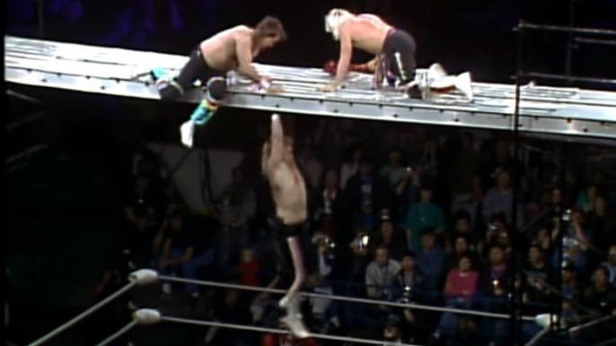 Bobby Eaton hangs off the scaffold as Robert Gibson and Ricky Morton move closer to knock him off at Starrcade '87