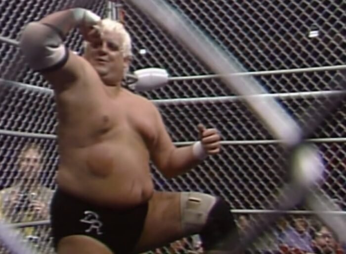 Dusty Rhodes flexes a muscle in the cage at Starrcade '87