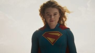 Milly Alcock as Supergirl floating in the sky, with a partial smile.