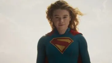 Milly Alcock as Supergirl floating in the sky, with a partial smile.
