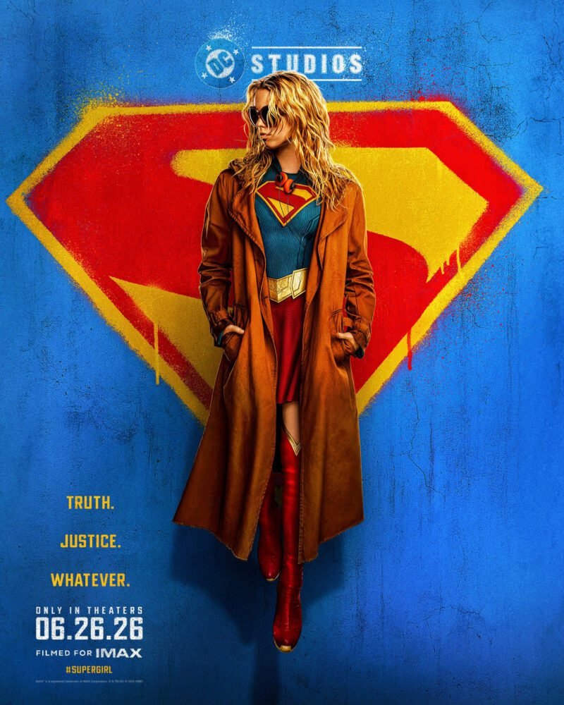 A poster of Supergirl, filmed for IMAX and only in theaters from 06.26.26. Milly Alcock's Supergirl floats in front of a graffitied crest on a rough blue wall. The following tag is on the bottom left of the image: Truth. Justice. Whatever.
