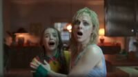 Karen (Cara Buono) and Holly Wheeler (Nell Fisher) with looks of fright on their faces. They are reacting to the demogorgon.