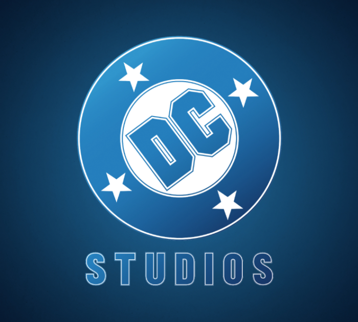 The logo for DC Studios on a blue gradient background. Text for "DC" is in blue and tilted in a white circle. The white circle has a blue circle surrounding it, with four white stars contained within. Below this circle, taken as a whole, is the word "Studios".