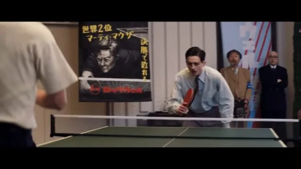 Marty prepares for one final game. He's standing behind one side of the ping pong table.