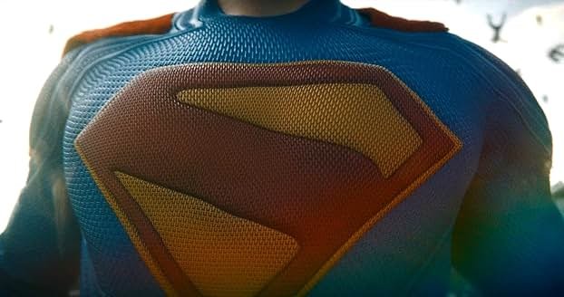 The crest of Superman takes up the majority of the shot, with the rest of the chest showing in the image. We do not see Superman's head - the image cuts off at the top just before then.