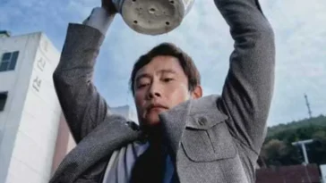 Yoo Man-soo (Lee Byung Hun) holds a plant pot aloft in a threatening manner in No Other Choice